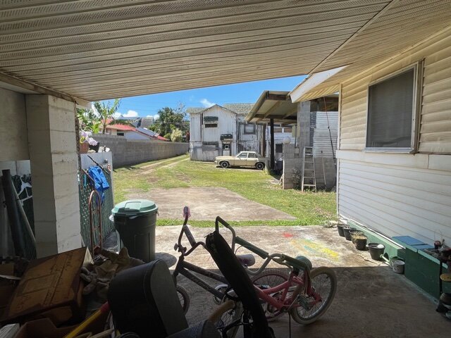 Looking out of the carport of a hawaii cottage toward the main home during the sale