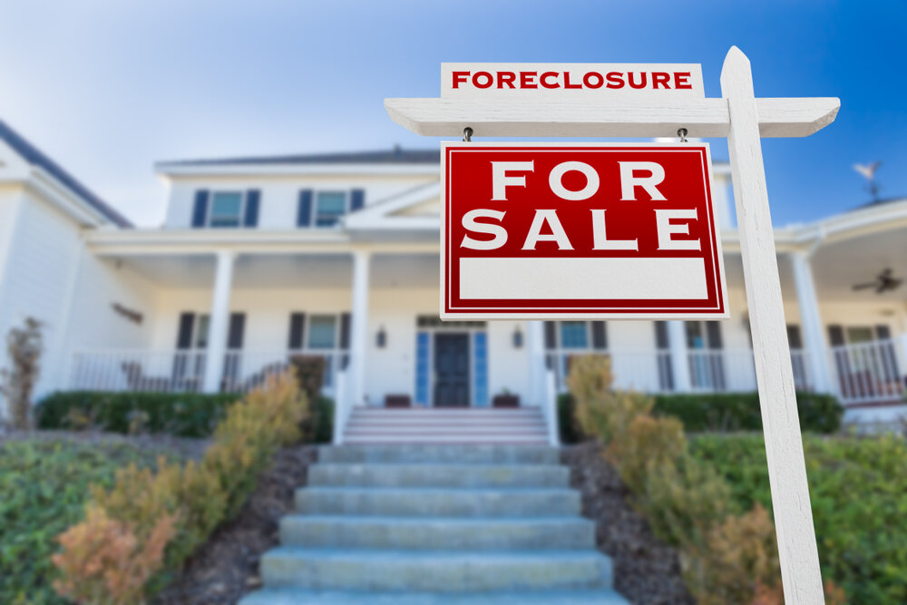 in focus "fore sale" sign in front of a house that is out of focus