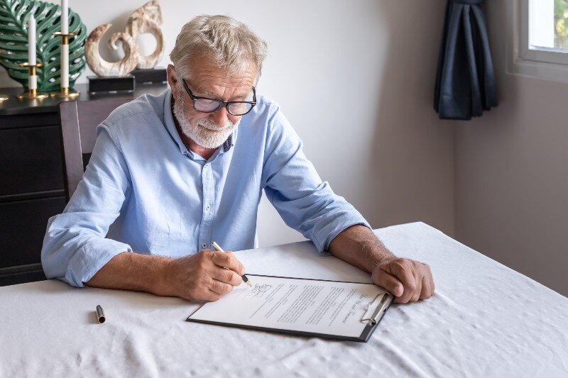 An elderly man signing a will.