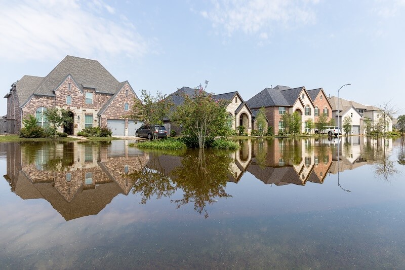 A row of large single-family houses in a flooded neighborhood