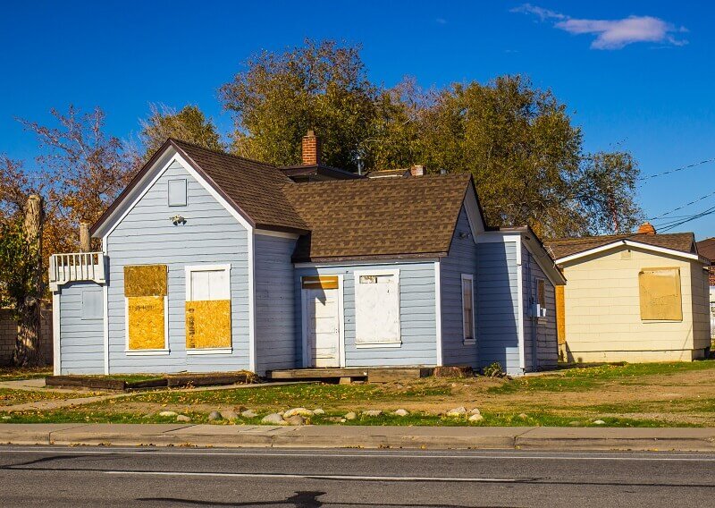 An old and condemned house with plywood in its window and door frames