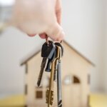 hand holding keys in front of a house after using five simple steps to selling your house fast with pitt home buyers in north carolina