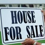 man straightening a house for sale sign while selling his house fast in Greenville nc