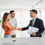 Real estate agent with couple shaking hands closing a deal