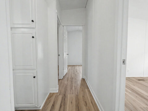 Clean hallway leading to the bedrooms with modern flooring inside the owner financed house at 105 Glenmont Ln.