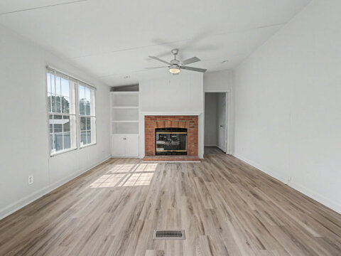 Cozy family room featuring a gas log fireplace and built-in bookcases available for owner financing in Greenville.