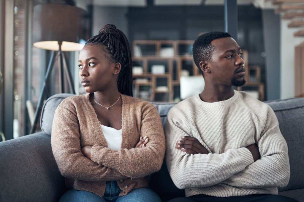Couple Sitting On Couch With Arms Crossed Looking Upset, Representing Homeowners In Lubbock Texas Going Through Divorce Or Separation Who Need To Sell Your House Fast For Cash