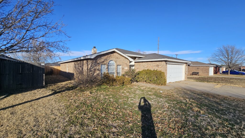 Brick House In Foreclosure Lubbock Texas With Garage, Front Yard, And Large Window, Showing That Cash Home Buyers Purchase Well-Kept Properties Too And Help Homeowners Sell Your House Fast For Cash