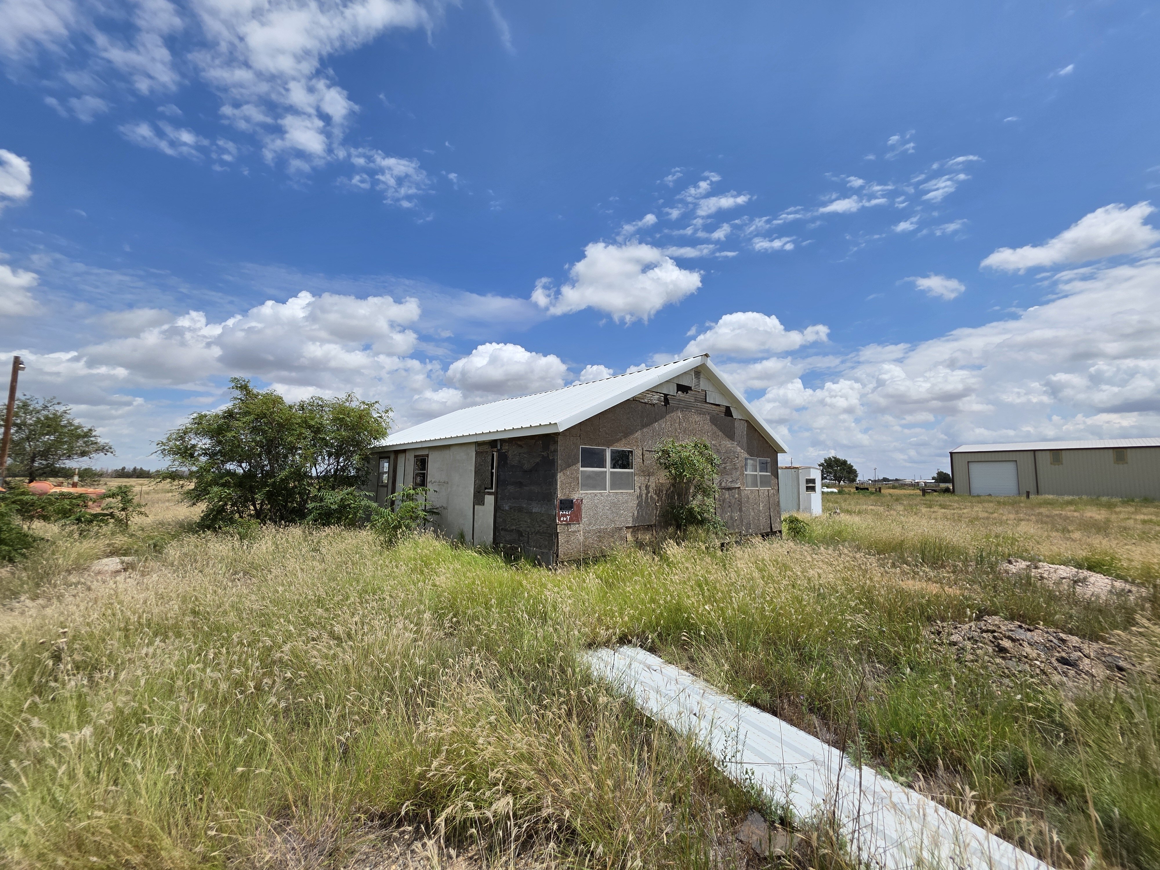 Old Abandoned House In Lubbock Texas With Boarded Windows, Damaged Siding, And An Overgrown Yard, Showing That Cash Home Buyers Purchase Properties In Any Condition And Help Homeowners Sell Your House Fast For Cash