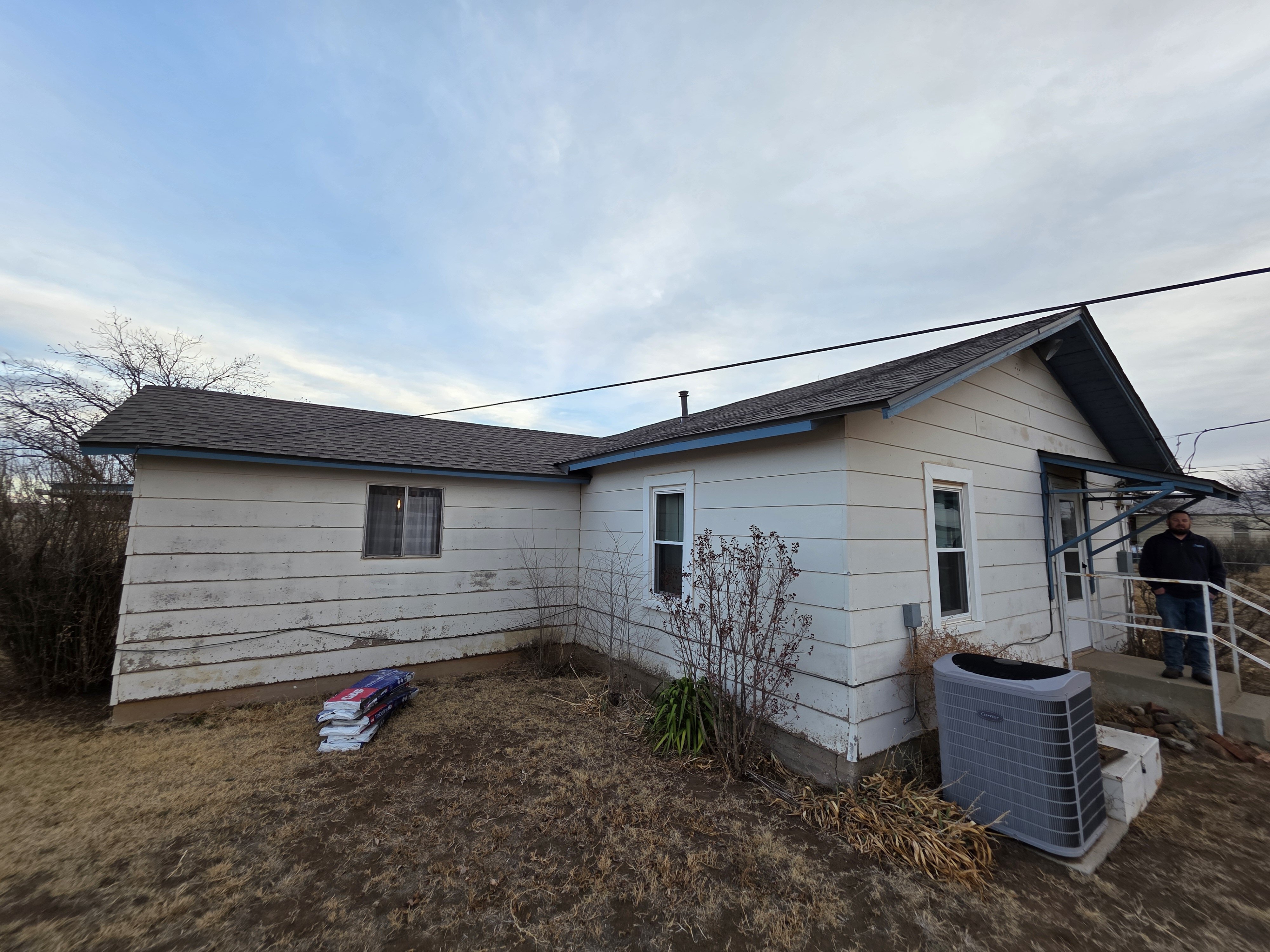 Distressed house in West Texas with worn exterior siding and yard, recently purchased by a local real estate investor for renovation