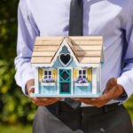 Person holding a model home outdoors, illustrating moving forward after inheriting a property you do not plan to keep.