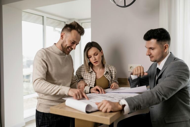 Three people at a table discussing documents and plans related to an inherited property.