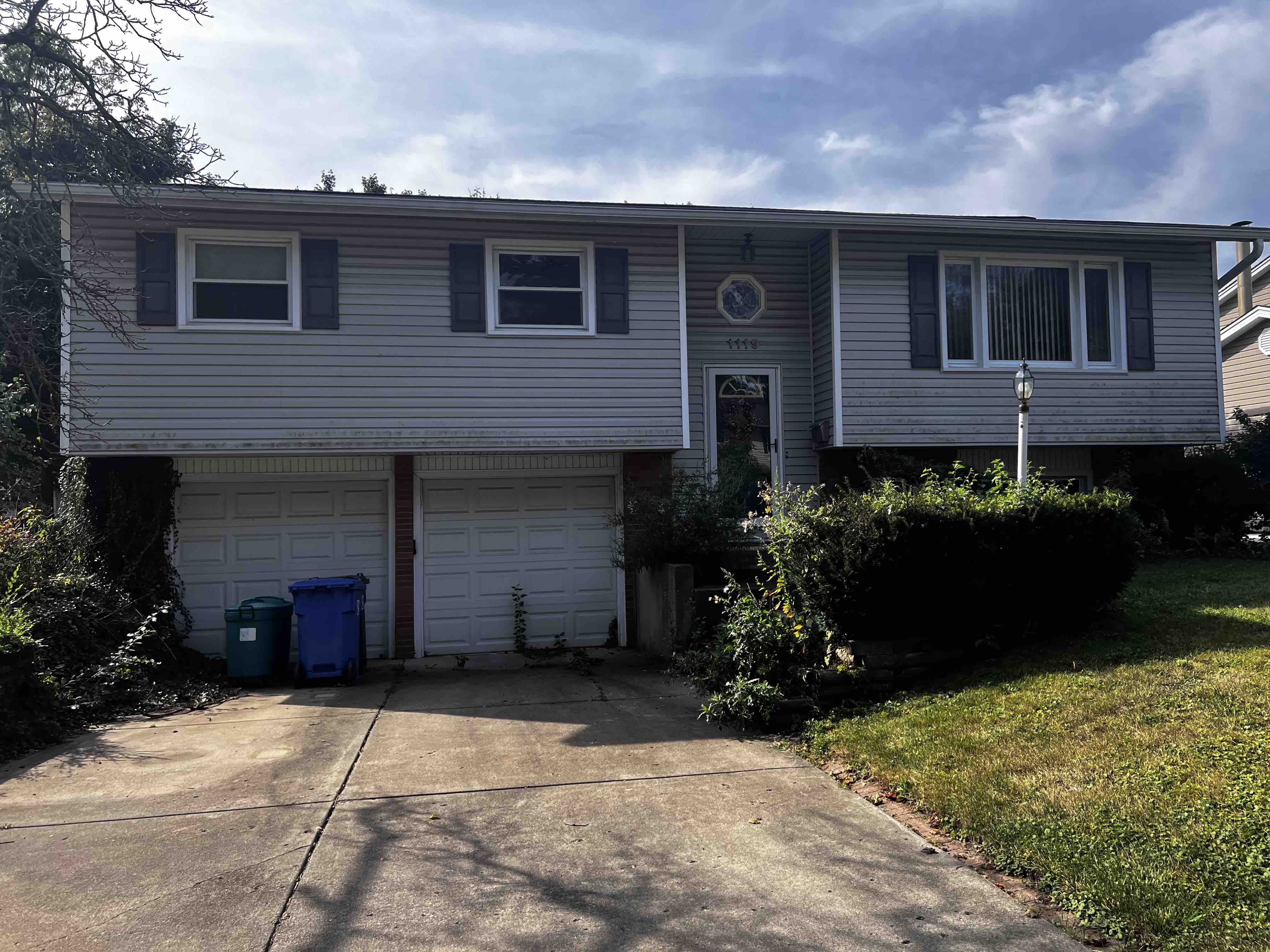 Outdated inherited home exterior in Rolling Meadows with peeling paint and overgrown landscaping