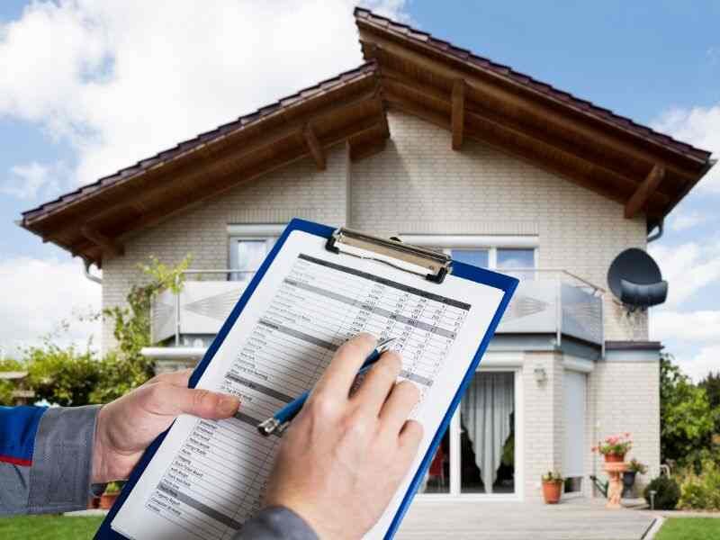 A professional appraiser with a clipboard assessing a property