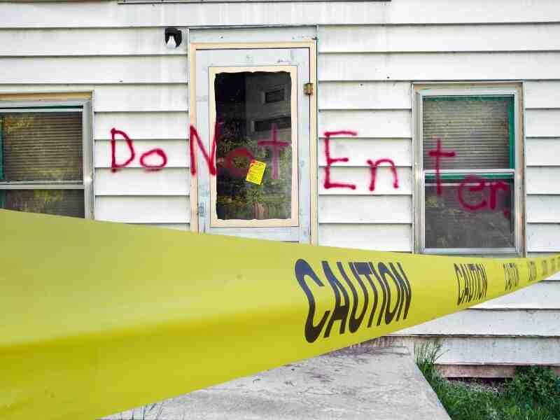 Condemned house with caution tape and structural damage