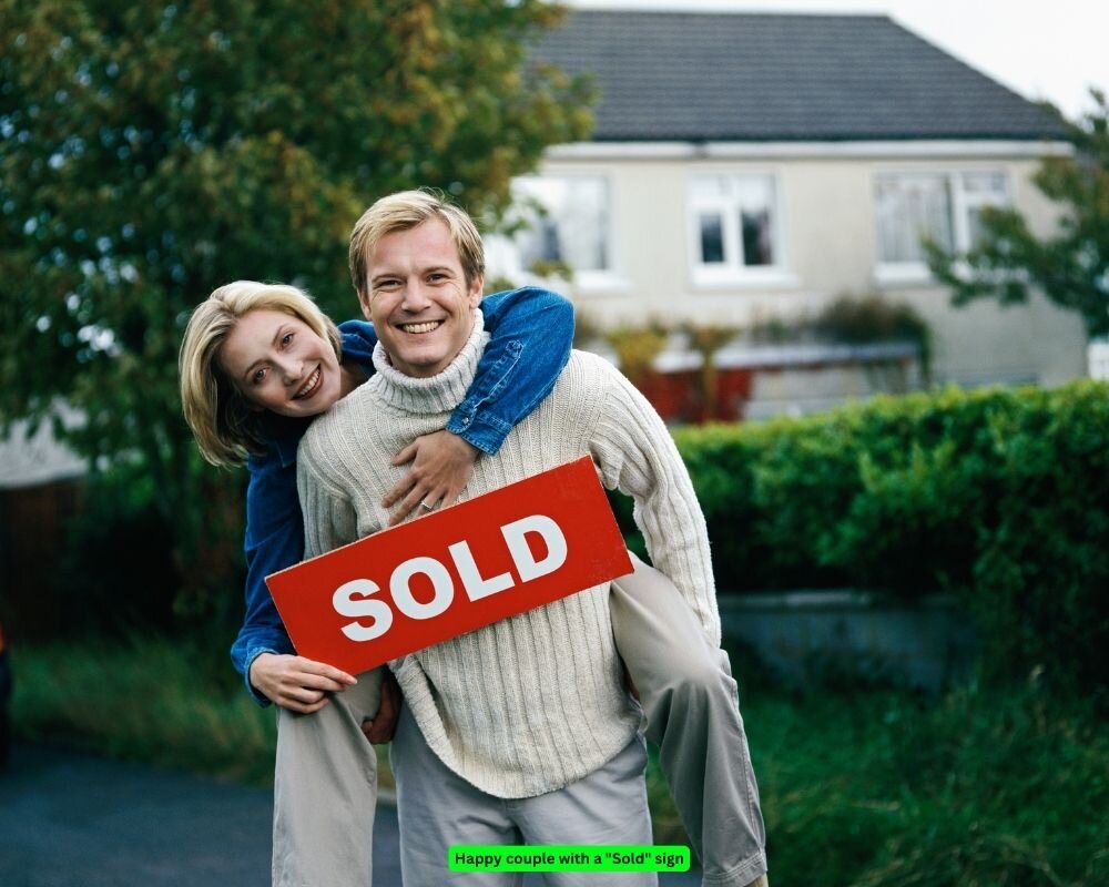 Happy couple with a "Sold" sign, indicating a successful home sale before moving out of state.