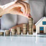 Person Stacking Coins To afford a house.