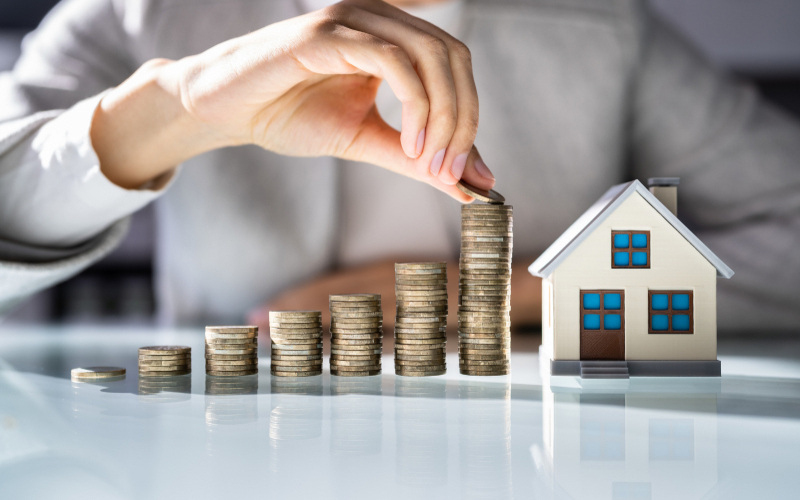 Person Stacking Coins To afford a house.