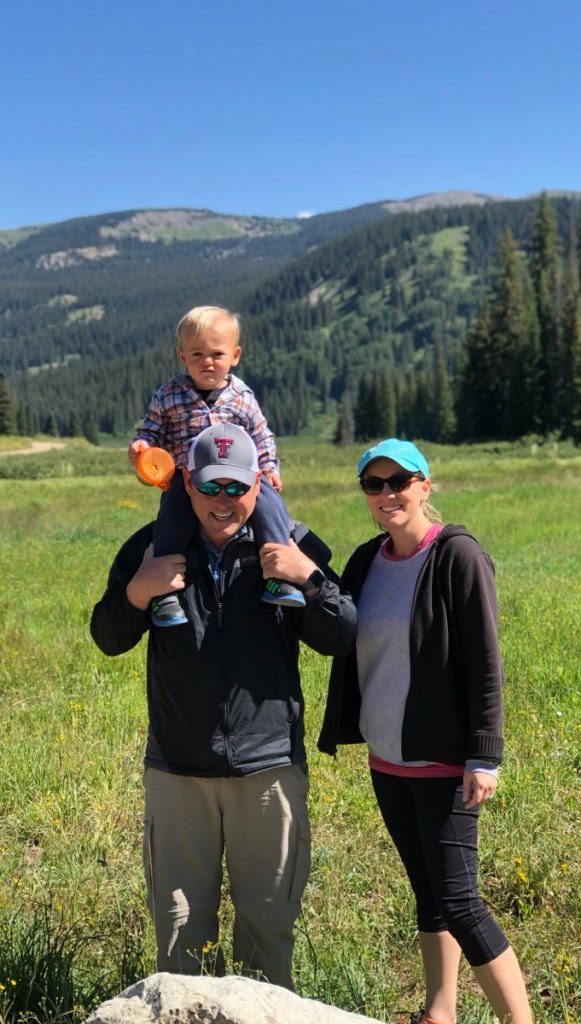 a family with the boy on his fathers shoulder the the hills as background