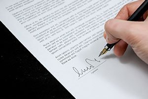 a hand signing a paper to close the sale of his house
