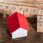 Property Tax Wooden Blocks With A Miniature House On Wooden Table