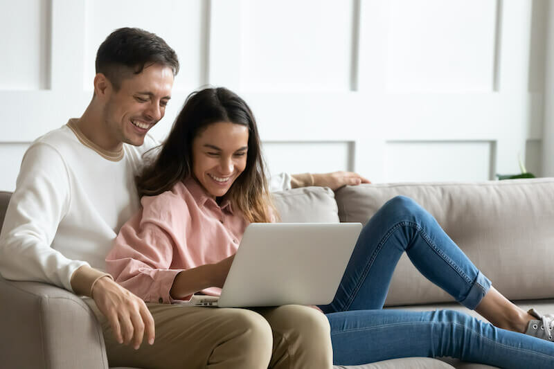 Happy young couple using laptop together, having fun on weekend in Wichita Falls Texas