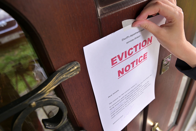 A woman placing an eviction notice on her house's squatters