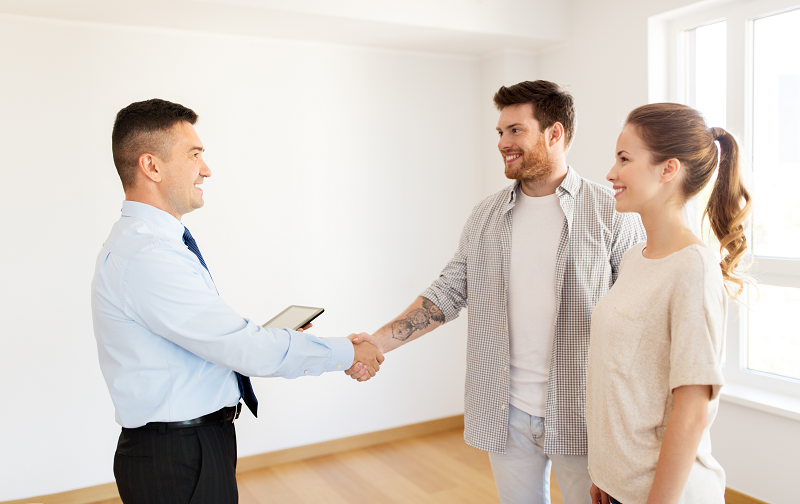 A young couple shaking hands after selling their house to a cash buyer