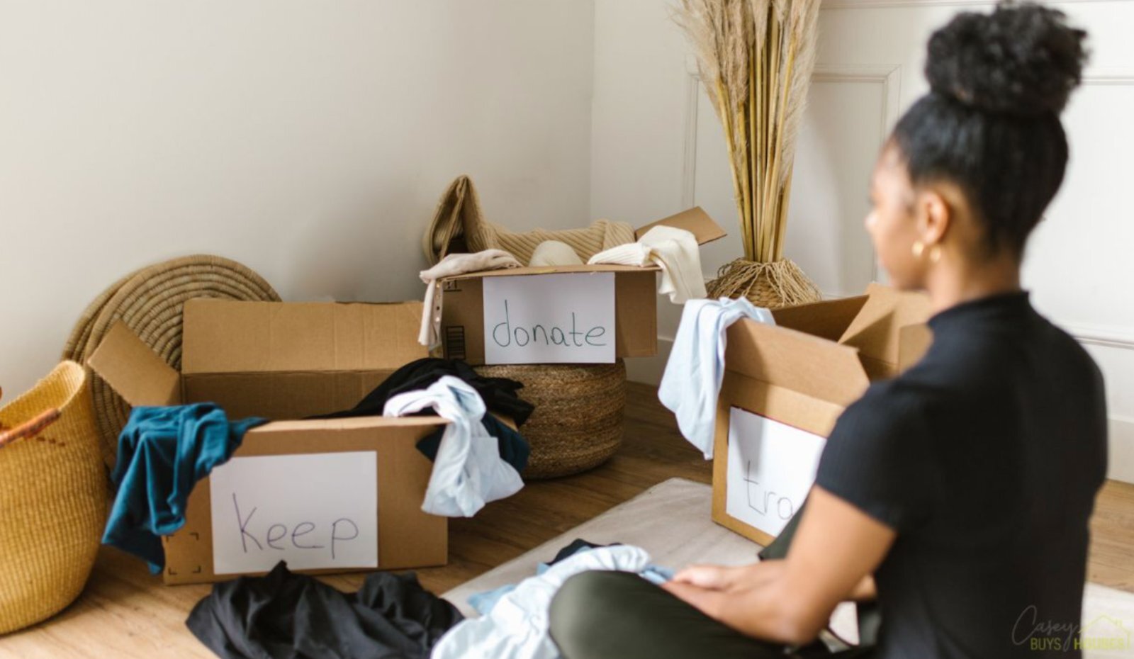 Homeowner sorting belongings into keep, donate, and trash boxes before selling