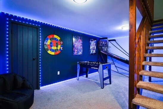 Rec room after rehab by Anna Buys Houses. with new lighting, games, new paint and carpet.