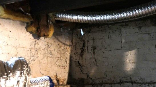 Water damage and crack in the foundation with light coming through on an Anna Buys Houses rehab project.