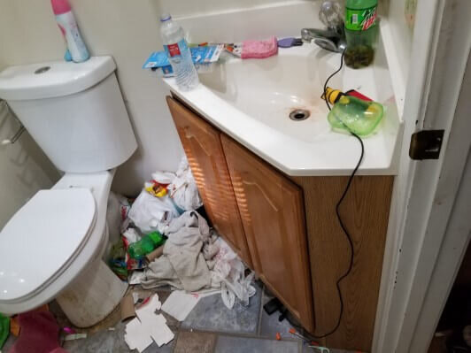 Master bathroom with garbage on the floor and stuff on counters. Needs to be cleaned and renovated.