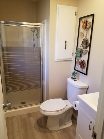 Master bathroom with new flooring, paint, vanity and shower, after an Anna Buys Houses remodel.