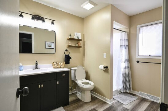 Master bathroom after rehab with new floors and updated sink and cabinets.