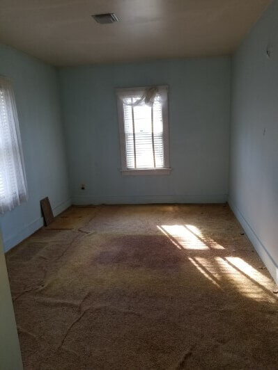 Old, stained carpet in a bedroom before rehab.