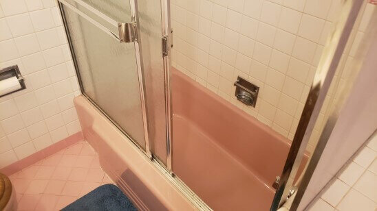 A dated pink bathtub and tile before renovation by Anna Buys Houses.