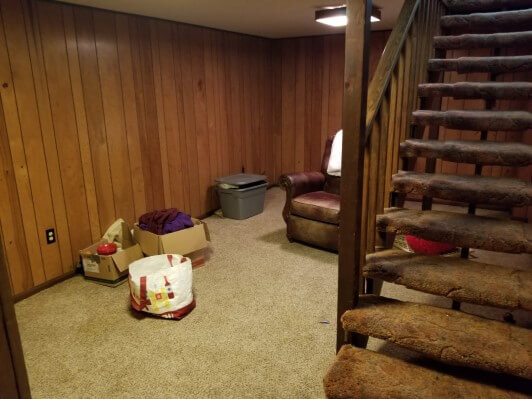 Rec room with old carpet and dated wood paneling before rehab by Anna Buys Houses.