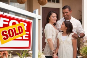 Hispanic Mother, Father and Daughter in Front of Their New Home