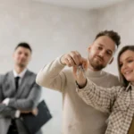 Couple receiving house keys from a real estate agent, illustrating selling a house with tenants without legal headaches.