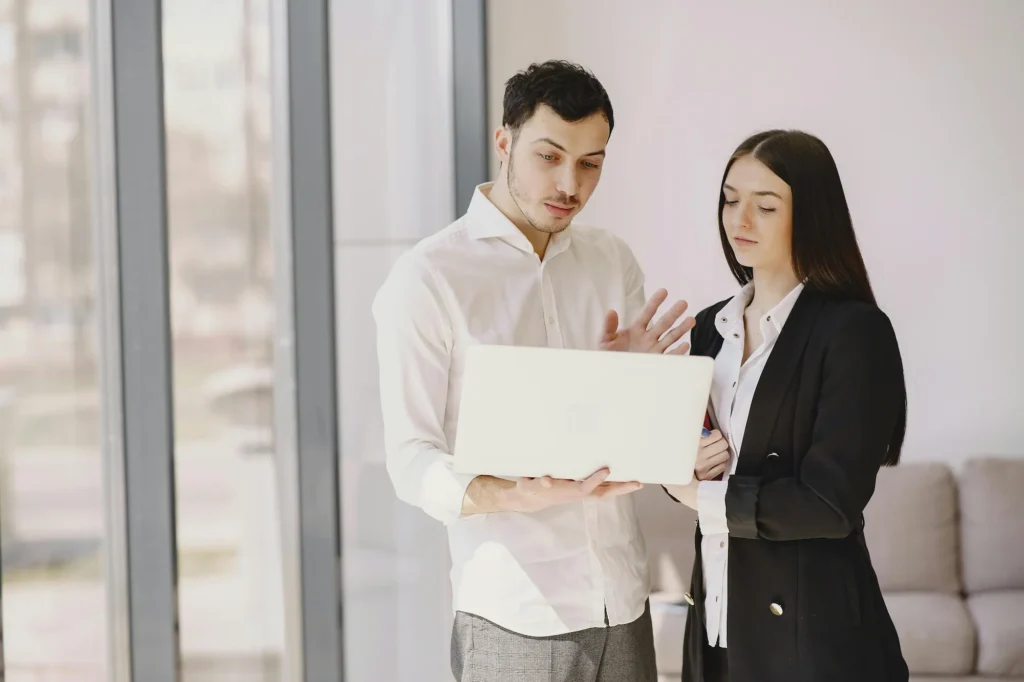 Two professionals review property details on a laptop during the planning stage of a tenant-occupied home sale.