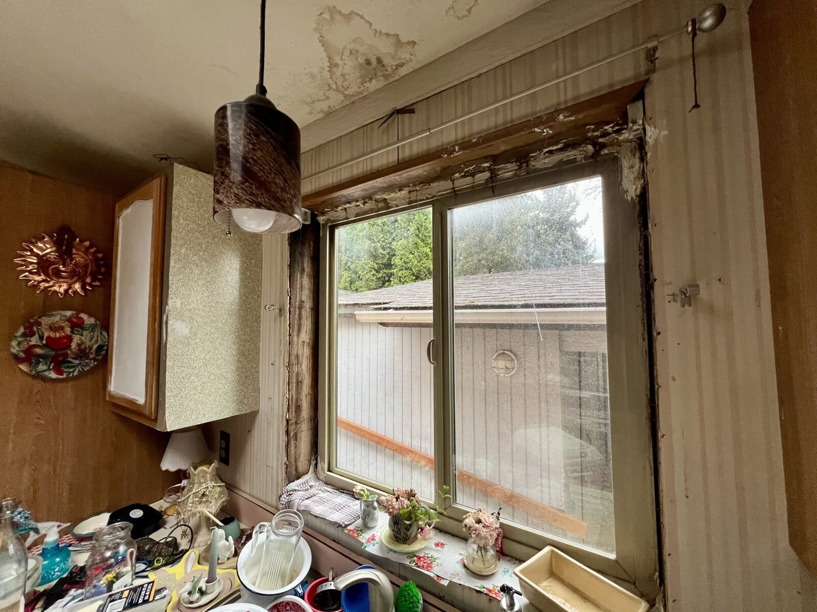 Kitchen of the Albany manufactured home with water stains on the ceiling and worn trim around the window