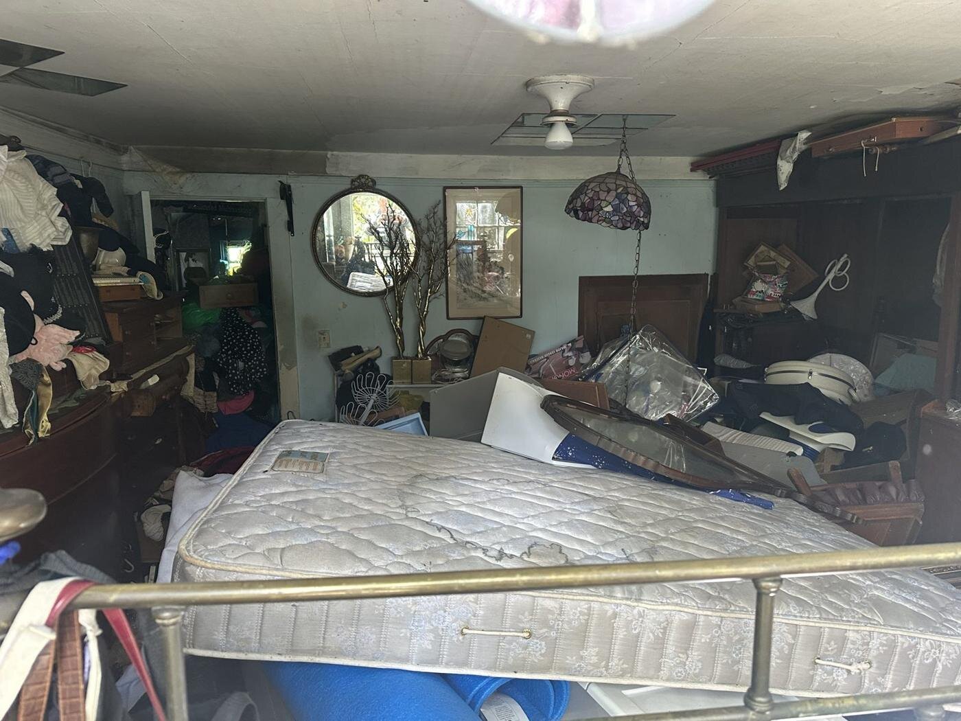 Bedroom in the Milwaukie house with a mattress, furniture and belongings piled up