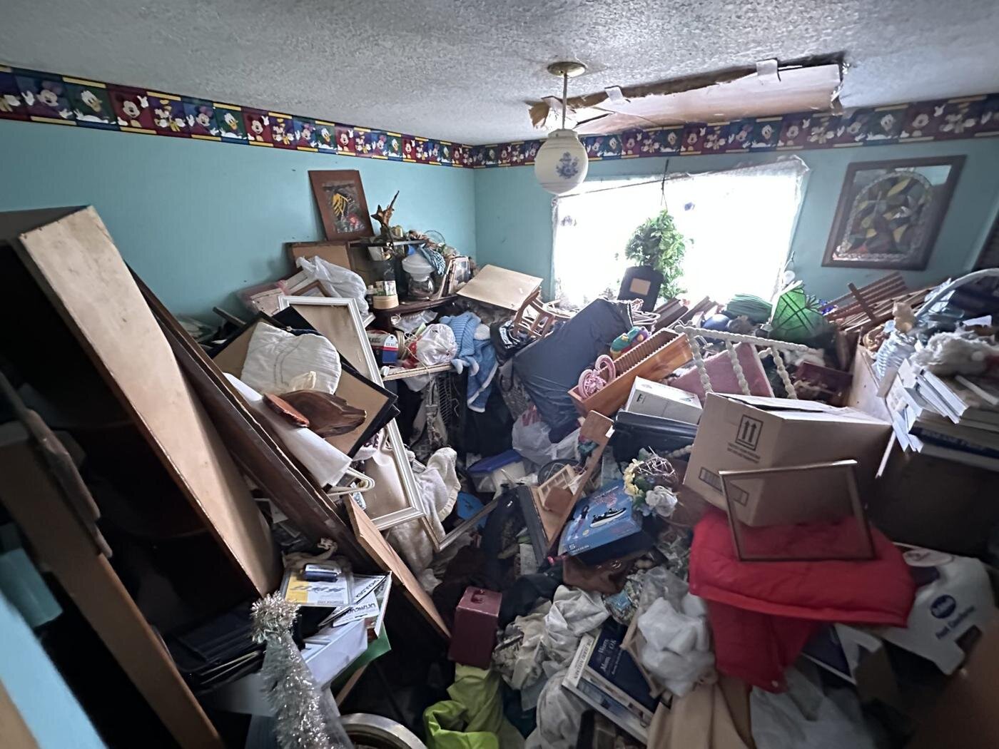 Room in the Craftsman house with belongings piled from floor to ceiling