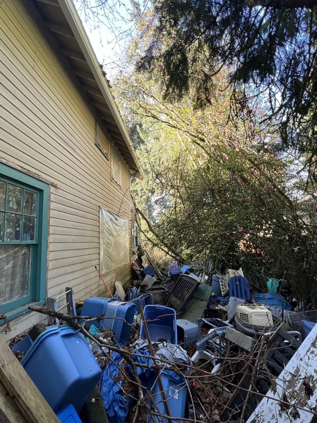 More belongings and debris piled along the side of the Craftsman house