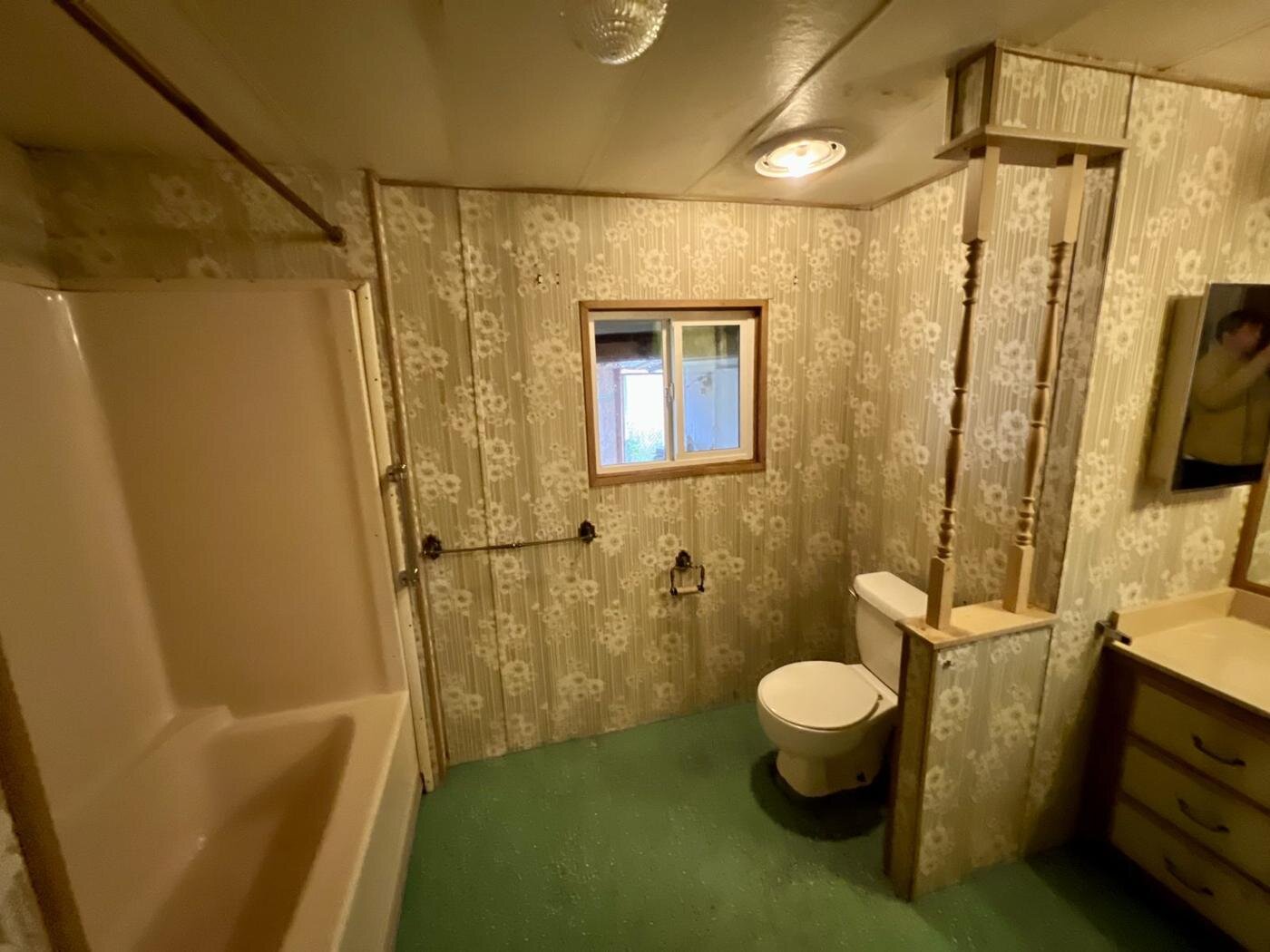 Bathroom with a tub, a toilet and a green carpet floor