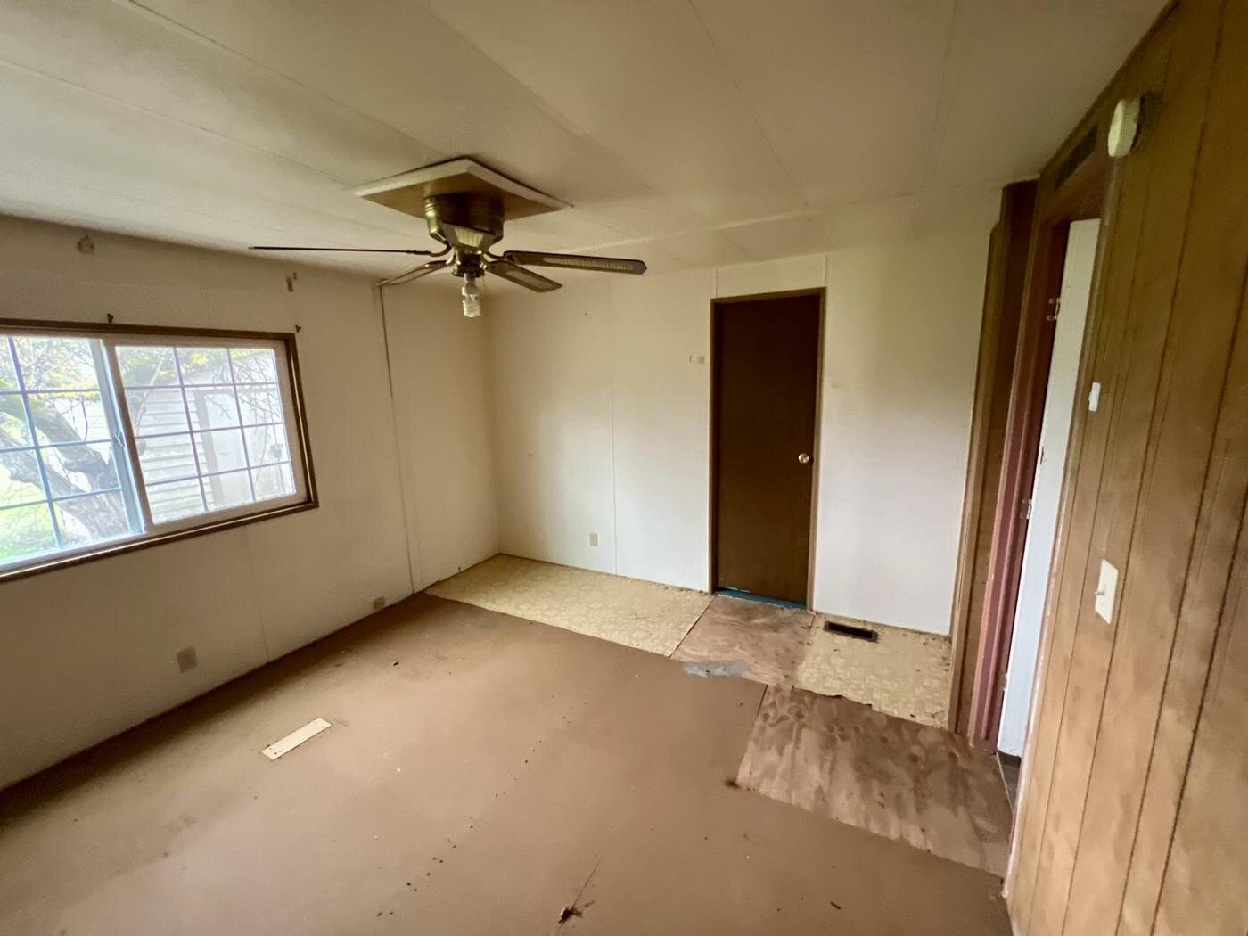 Bedroom with worn subfloor and missing flooring in the Salem manufactured home