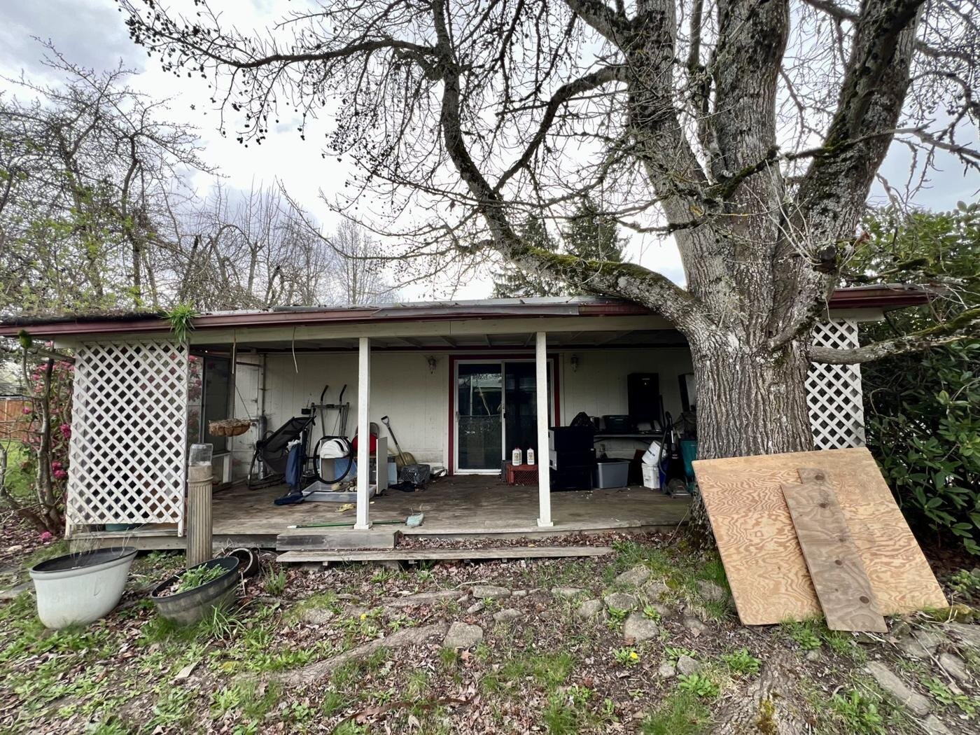 Rear covered porch of the inherited manufactured home in Salem, Oregon, with a large tree beside it