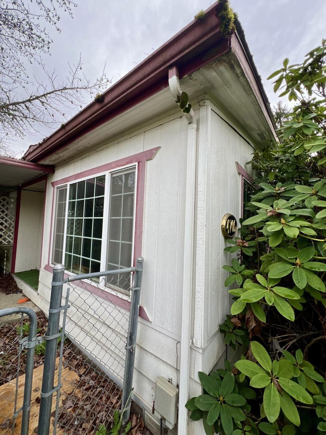 Side of the Salem manufactured home with maroon trim and a chain-link fence