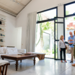 Engaged in conversation, a home seller asks a house flipper detailed questions about the potential sale, eager to understand the flipping process and the benefits it could offer them.