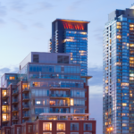 This photo captures a vibrant urban skyline with a mix of contemporary high-rise condominiums. The buildings feature sleek glass facades, reflecting the evening light and creating a dynamic and modern atmosphere.